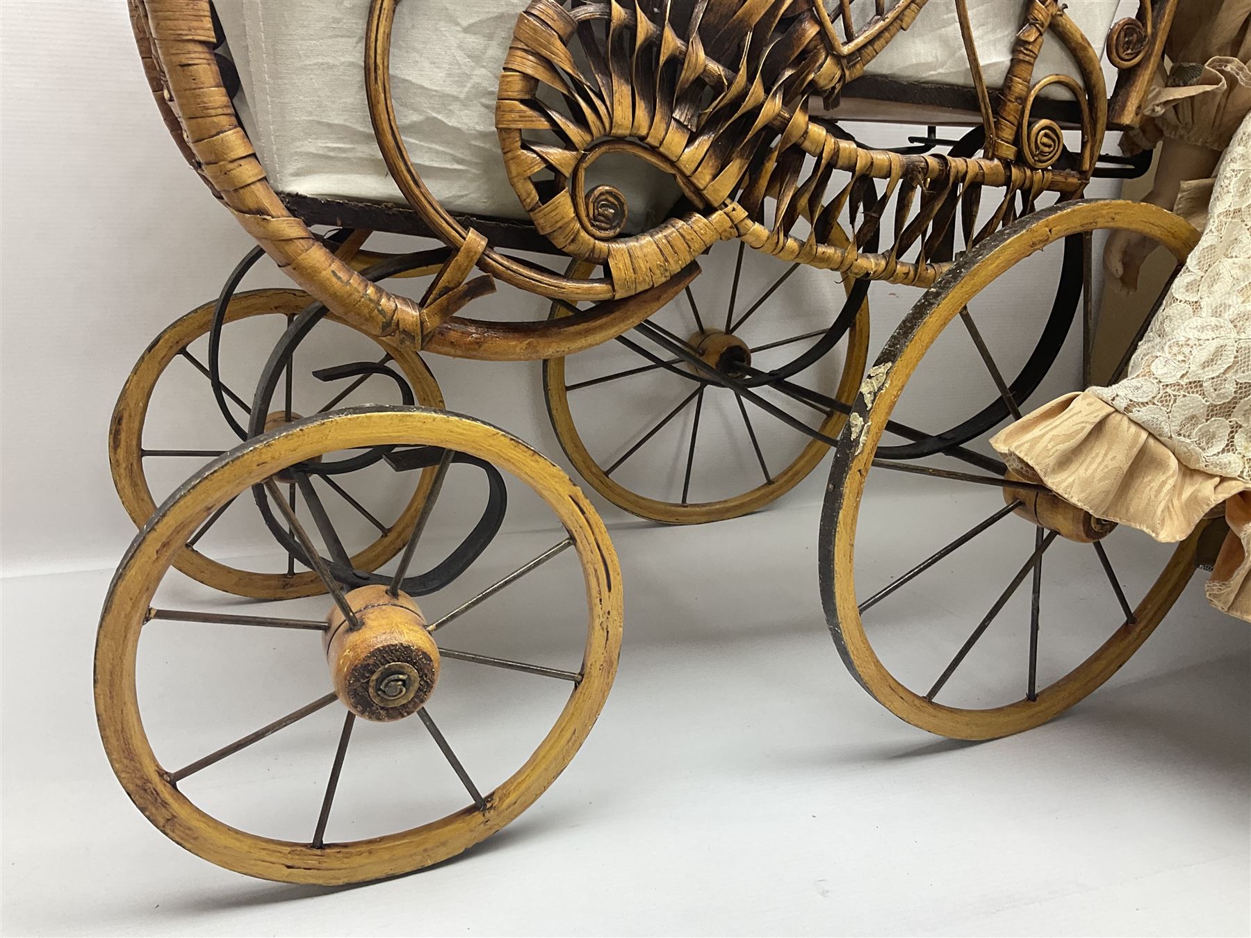 Two decorative wicker dolls prams, one with lace parasol,  and eleven dolls, including Leonardo Collection porcelain dolls, tallest pram including parasol H105cm