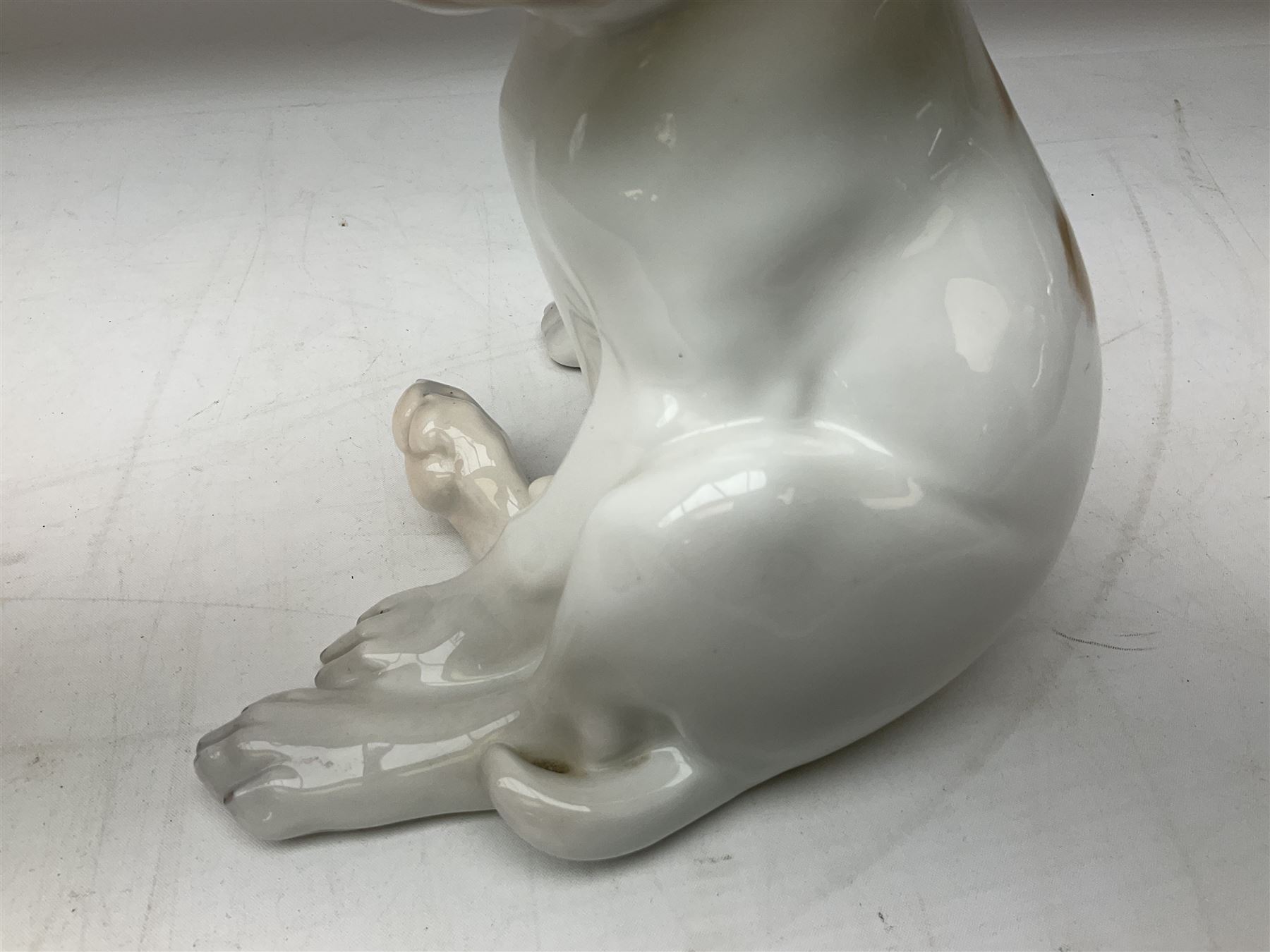 Royal Copenhagen figure of a pointer puppy, modelled seated with rare white and brown patch colourway, designed by Erik Nielsen, model no 259, date code for 1889-1922, with printed and painted marks beneath, H19cm