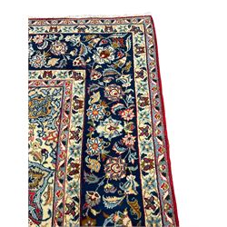 Large Persian Kashan carpet, the red ground field decorated with floral central medallion and spandrels, overall floral design depicting trailing branches with stylised plant motifs, guarded blue ground border with stylised flower head motifs