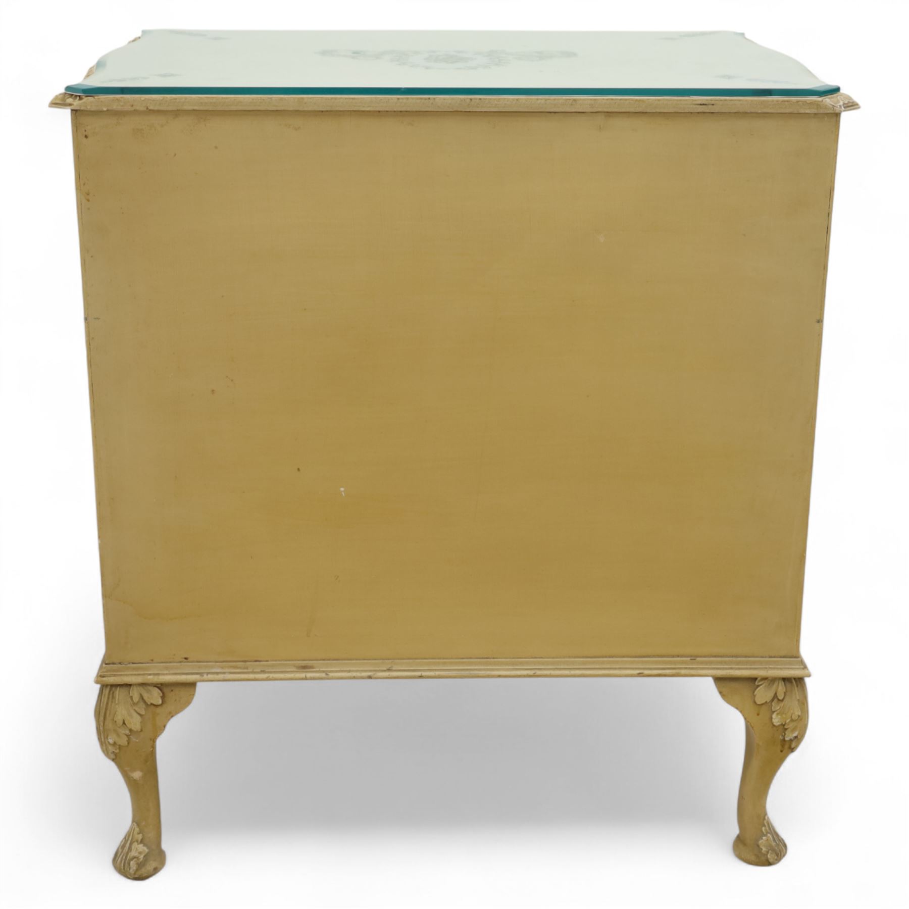 French design cream painted three drawer commode, shaped front with floral garland appliqués, fluted uprights and acanthus carved cabriole legs terminating in scroll feet