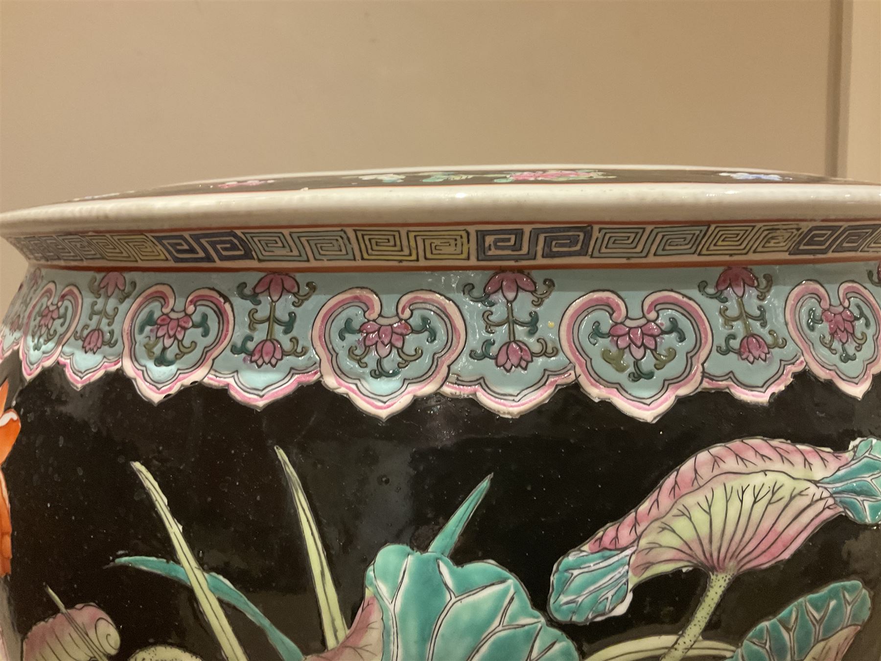 Large 20th century Chinese famille noir glazed porcelain jardinière, of ovoid form, the exterior enamelled with butterflies and white cranes amidst blossoming water lilies and pads against a black ground, between two stylised polychrome borders and beneath a key border to rim, the interior enamelled with red koi fish swimming amongst water fronds and weeds, with printed red character mark beneath, the whole upon an ebonised hardwood stand with three cabriole legs, jardinière H42cm D47cm, including stand overall H69.5cm