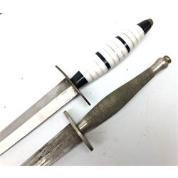  WW2 Fighting Knife, 17.5cm tapering steel twin edge blade with oval cross guard, chequered grip with circular top-nut, L30.5cm, in leather sheath and another with 17.5cm tapering steel twin edge blade brass oval guard, later black & white perspex grip with circular top-nut, L29.5cm in leather sheath, (2)  