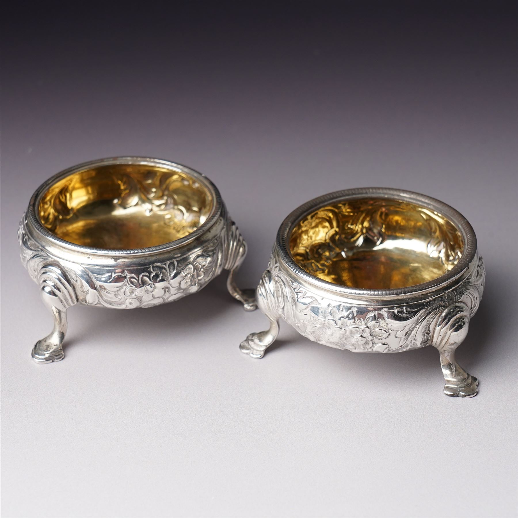 Pair of George III silver circular salts with gilded interiors and embossed decoration and two 19th century condiment spoons, one by Peter and Ann Bateman 