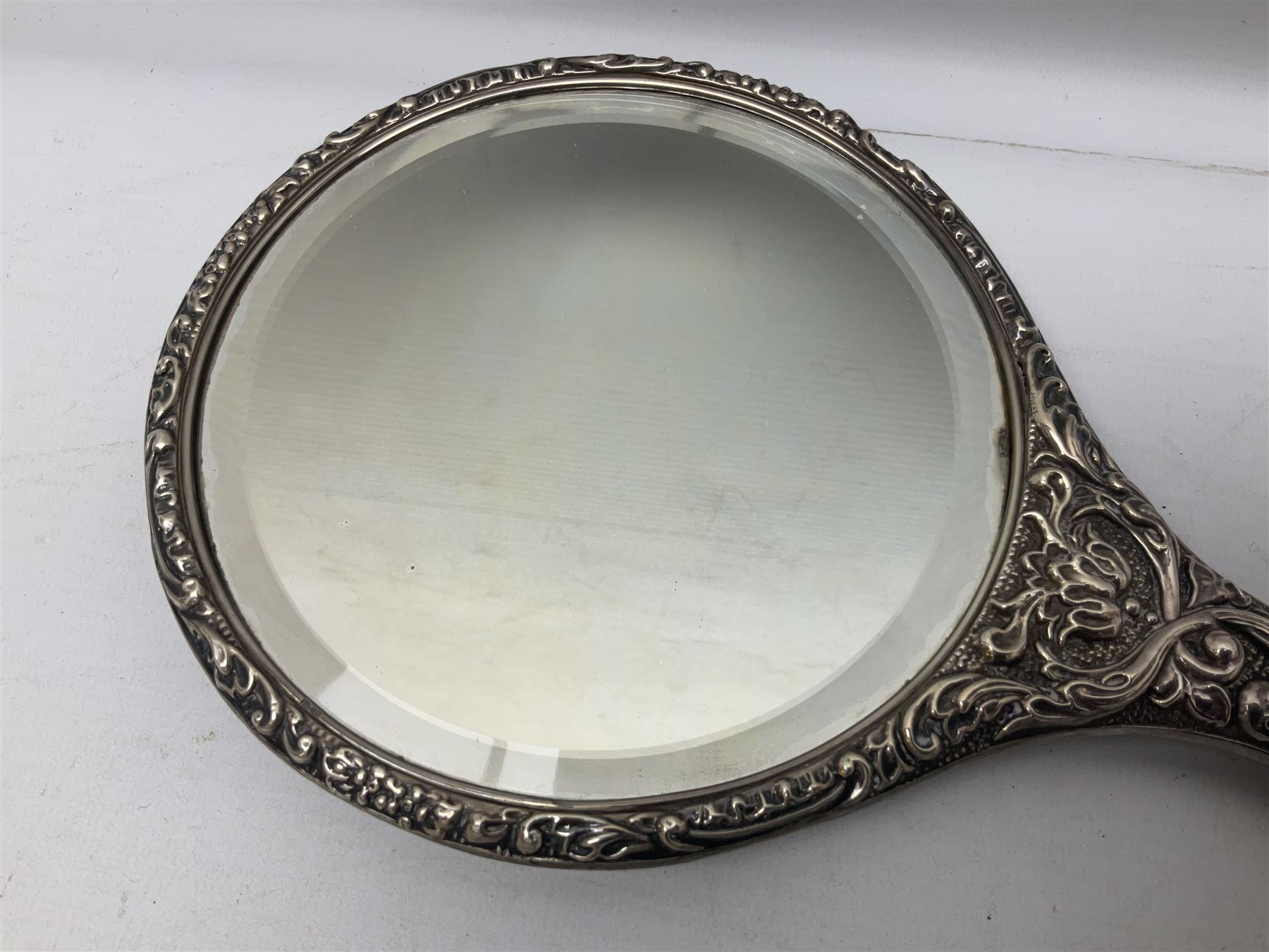 Silver mounted dressing table mirror, embossed with birds, masks, and foliate and C scrolls, hallmarked Birmingham, and fruit knife with mother of pearl handle and silver blade, (2)