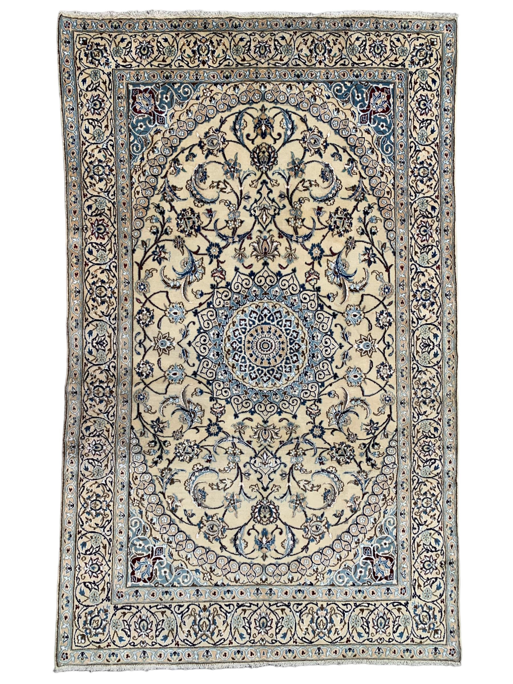 Persian Kashan ivory ground rug, central medallion surrounded by scrolling leafy branches and stylised flowerhead motifs, scrolling border decorated with further stylised plant motifs