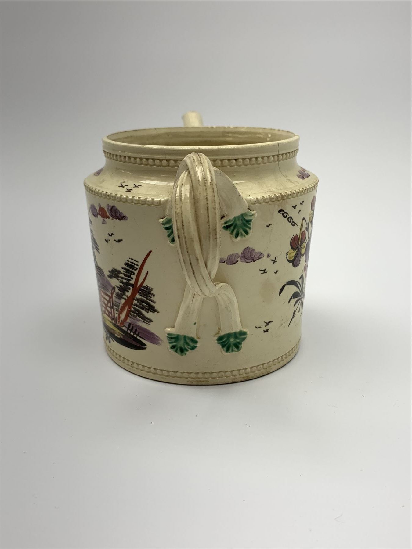 18th century creamware teapot, probably Leeds, with reeded entwined handle and floral finial to the cover, the body with hand painted polychrome decoration of figure to one side, and floral spray to the other, collectors paper label beneath inscribed Leeds Pottery, H11.5cm
