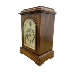 Edwardian - 8-day mantel clock in a mahogany case with satin wood inlay, flat toped case with an arched glazed door, silvered dial with engraving, Arabic numerals, minute track and steel spade hands, strike/silent feature to the arch, movement striking the hours and half hours on four gong rods.
With pendulum.