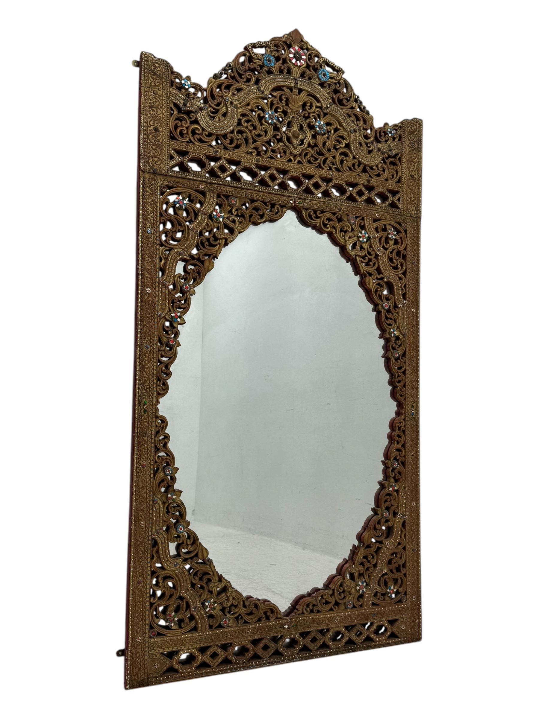 Large North African design carved and painted wall mirror, decorated with floral motifs, pierced foliate scrolls, inset mirrored panels, and colourful painted detailing, enclosing an oval bevelled mirror plate