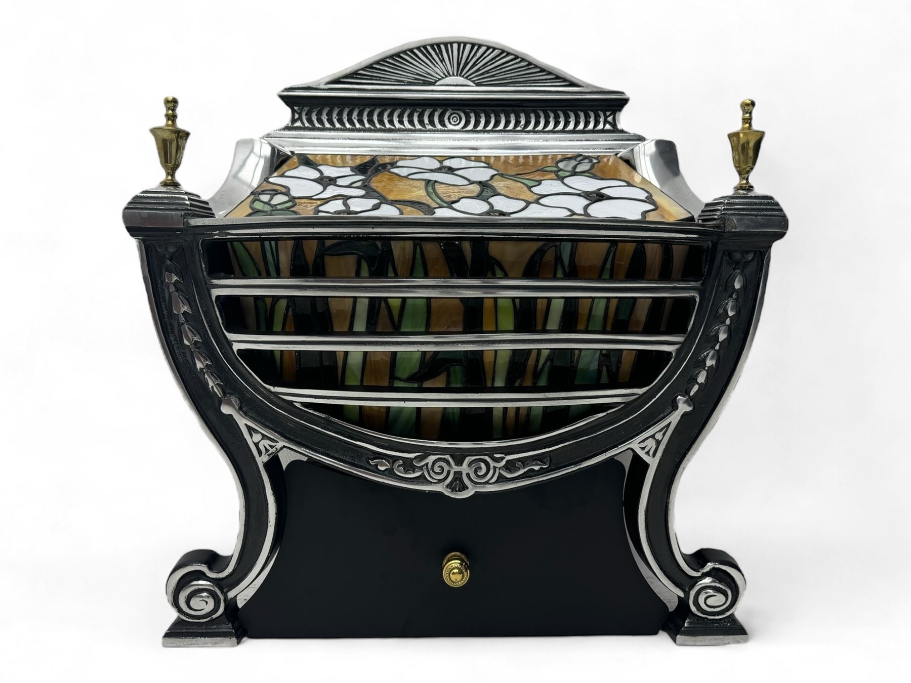 Stained glass and cast iron electric fireplace, arched top with decorative finials, stained glass front panel with floral motifs, flanked by cast iron scrolls, raised on scroll supports