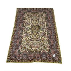Central Persian Kirman ivory ground rug, decorated all-over with flower heads and trailing foliage, shaped pink and blue ground borders with olive green outer band