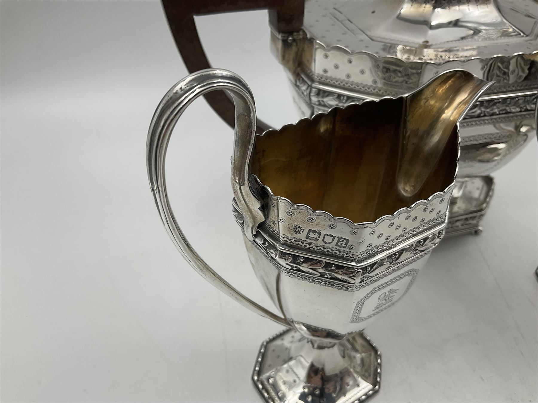 Victorian silver four piece tea service, comprising teapot, teapot stand, twin handled open sucrier and milk jug, each of octagonal form with foliate bud border and engraved decoration including crest to canted panels, and vacant panels, the teapot with ivory finial to the hinged cover and later wooden handle, hallmarked Edward Barnard & Sons Ltd, London1896, teapot including finial H15cm, milk jug including handle H16cm, teapot stand W11.5cm

This item has been registered for sale under Section 10 of the APHA Ivory Act