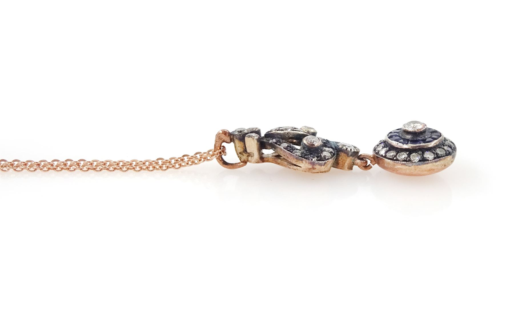 Gold and silver sapphire and diamond pendant, single round brilliant cut diamond, surrounded by calibre cut sapphires and round brilliant cut diamonds, suspending from a fancy pendant set with further diamonds, on a rose gold plated silver chain necklace, total diamond weight approx 0.60 carat