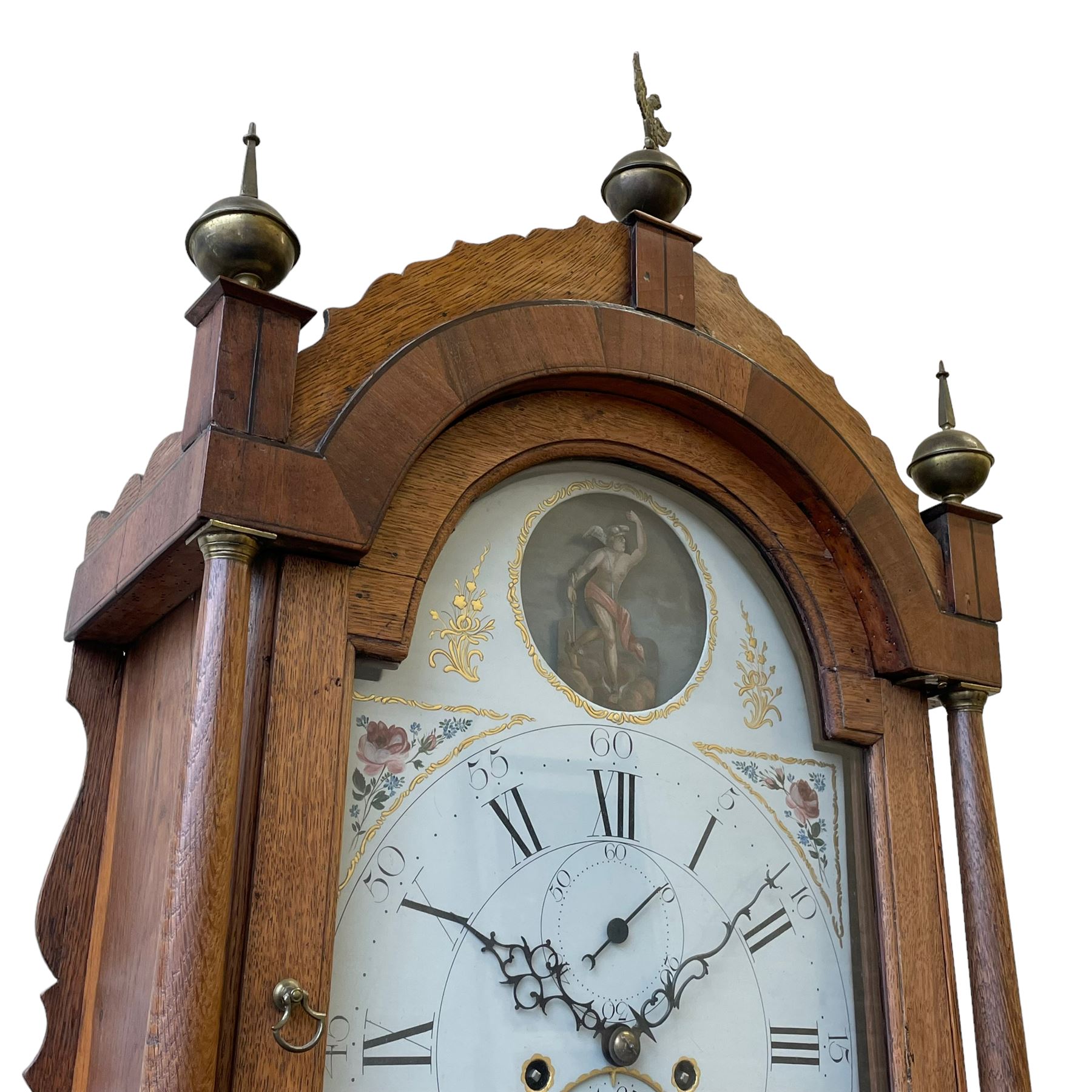 William Gostling of Diss  (Norfolk)-  Late 18th century 8-day oak longcase clock c1780-90, break arch top with scalloped cresting and three brass finials, glazed break arch hood door flanked by turned pilasters with brass capitals, trunk with a long trunk door and rounded top on a square plinth with an applied and shaped skirting, early painted Wilson of Birmingham dial with Roman numerals and five minute Arabic's, matching steel hands and second pointer, arched square ended calendar aperture with date disc behind, floral spandrels within gesso borders and a painted rocking automaton representing Mercury to the break arch, dial pinned via a false plate to a weight driven rack striking movement with a recoil anchor escapement, striking the hours on a cast bell. With pendulum weights and key. 
William Gostling (II) is recorded as working in Diss from 1774 to 1797, succeeded by widow Anne and son George . The dial of this clock is illustrated and discussed in detail in M.F. Tennants book 