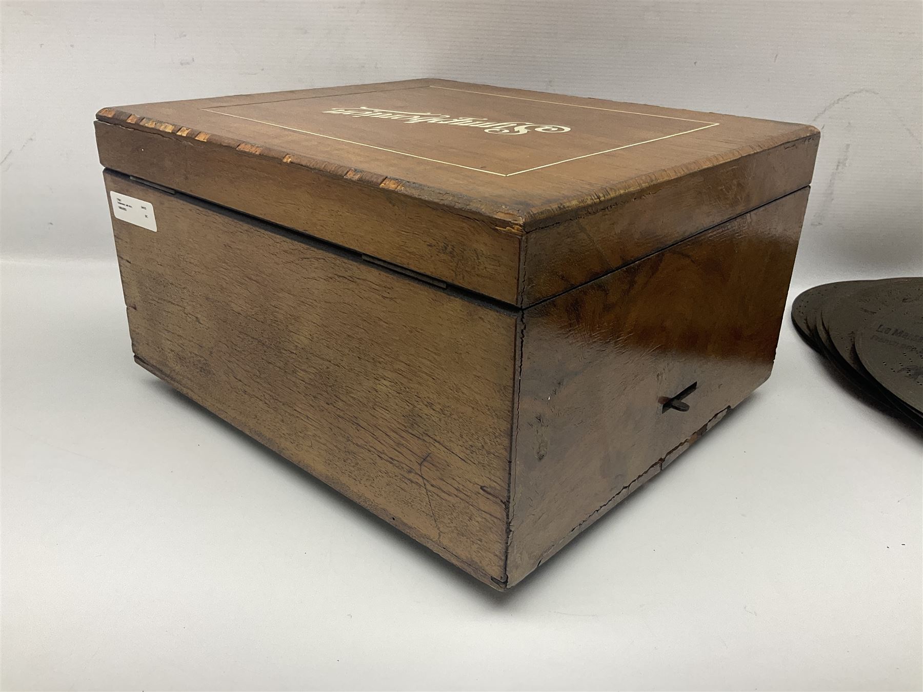 Late 19th century Symphonion disc musical box for spares or repair, inlaid walnut case with front lever action, playing 25.5cm discs on a 10.5cm steel comb with forty-nine teeth, musical scene of cherubs under the lid, L33cm; together with twelve 25.5cm discs