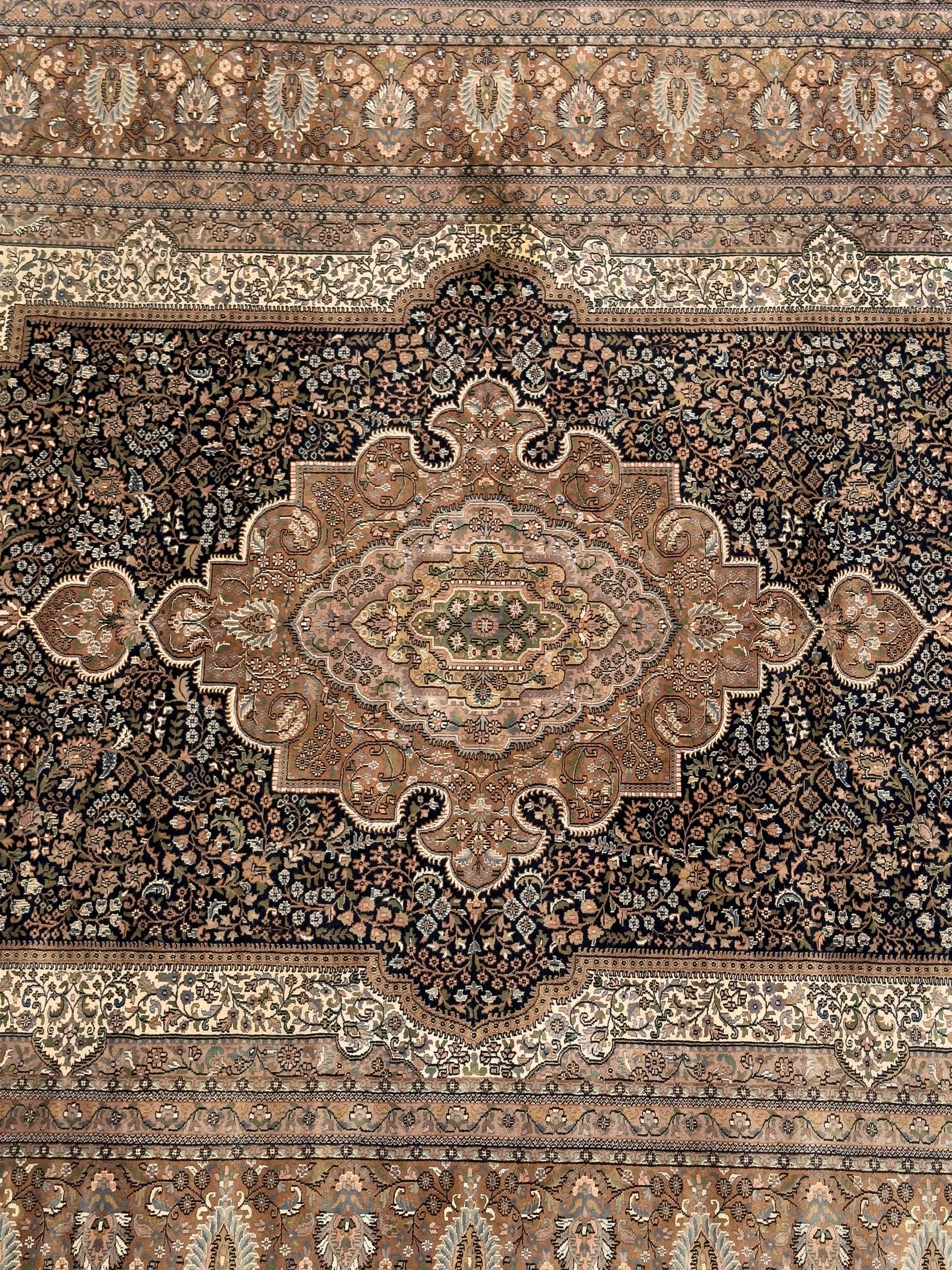 Large Persian indigo ground rug, the busy field decorated with trailing branches and flower heads, peach border decorated with palmettes -