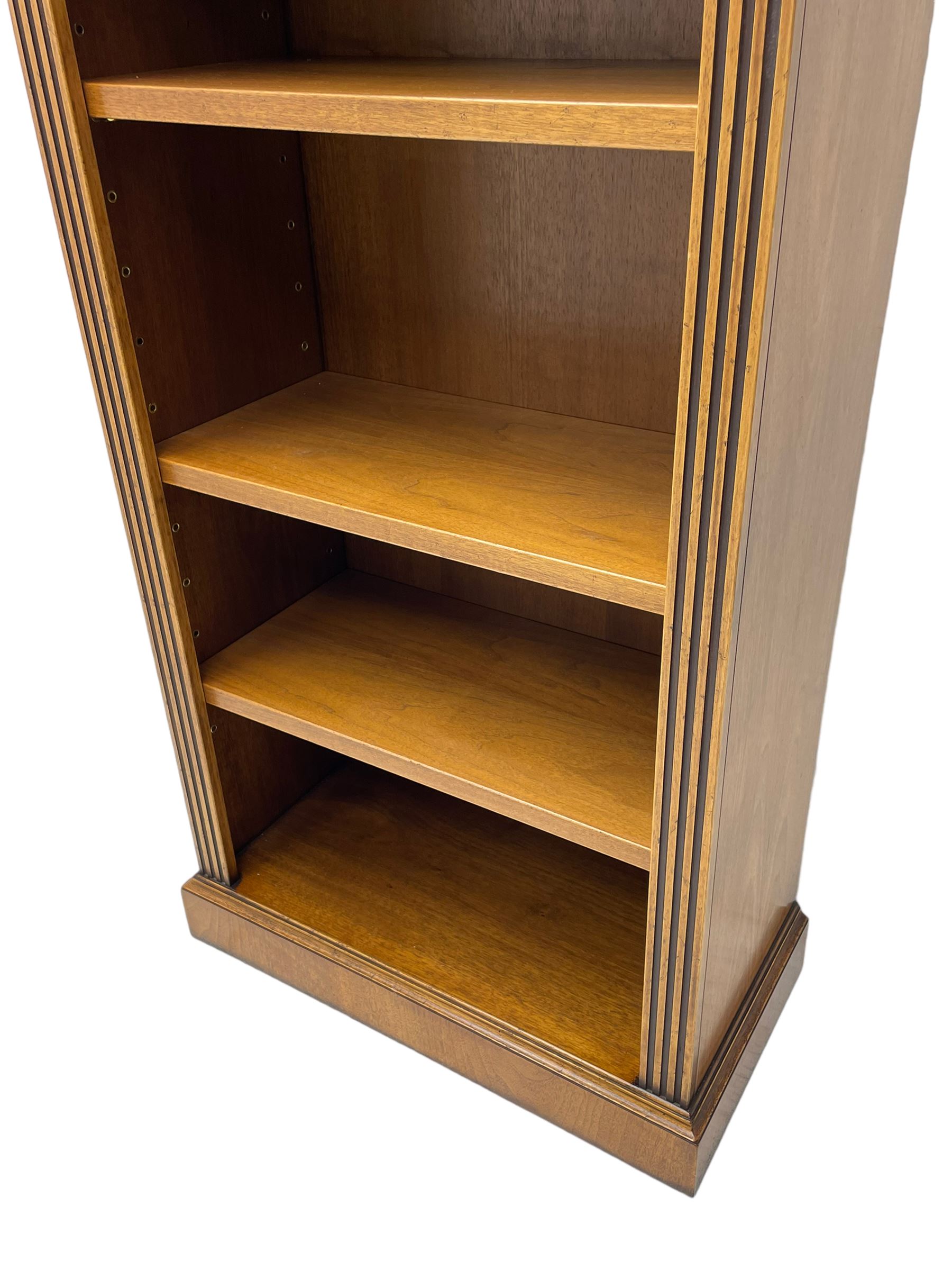 Georgian design walnut open bookcase, projecting cornice over figured banded frieze flanked by roundels, fitted with six adjustable shelves with flanking fluted uprights, on skirted base