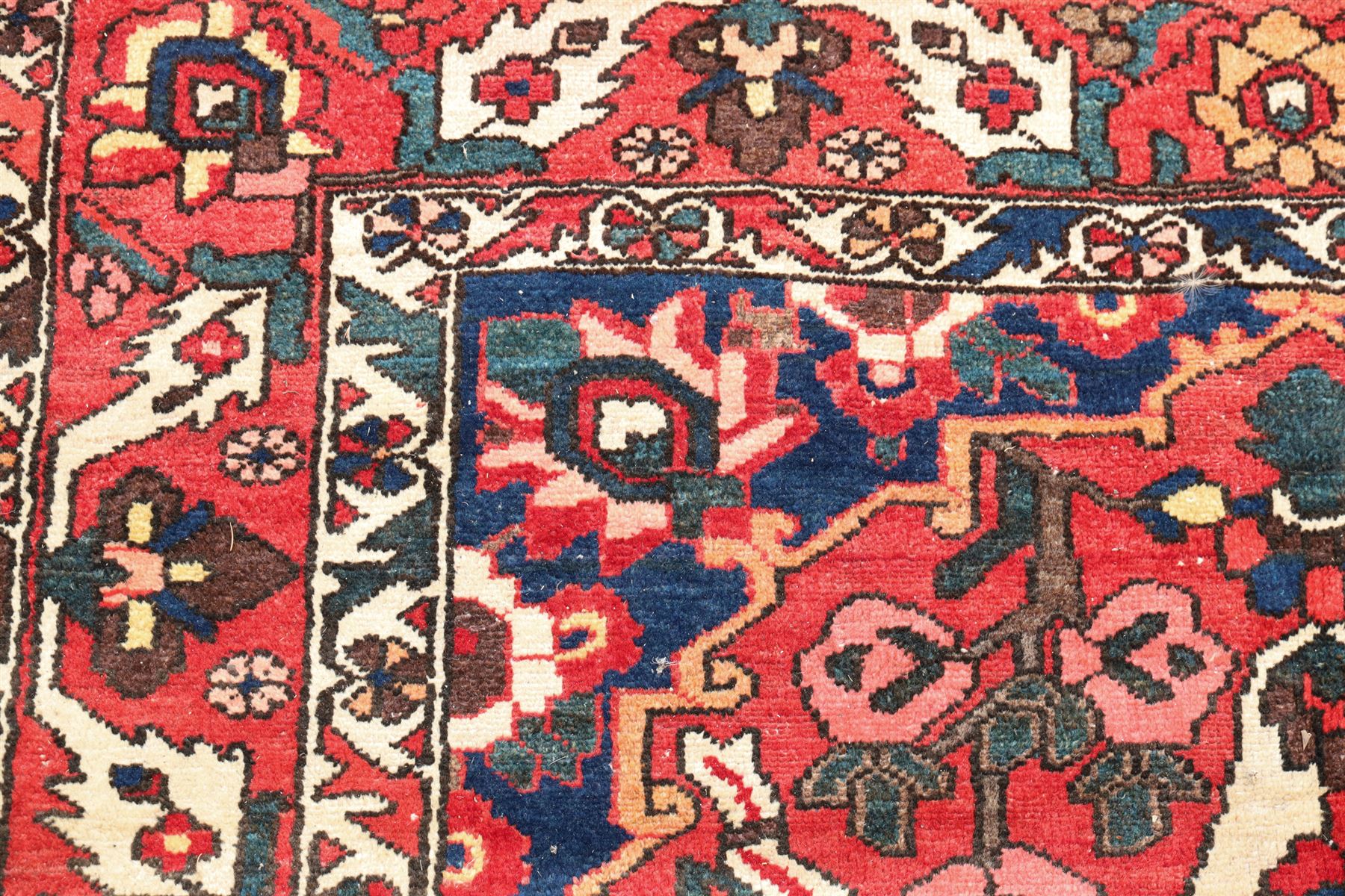 Vintage Persian Heriz crimson ground rug, the field decorated with a central stylised urn and bird of paradise motifs, the guard  lines with repeating stylised plant motifs of geometric form
