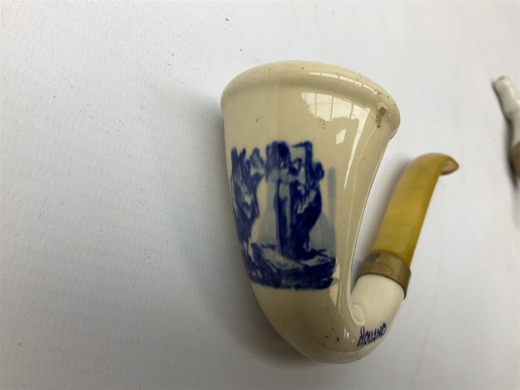 Carved meerschaum and amber pipe with silver mount, the bowl carved as a woman, cased, clay pipe in the form of an acorn, ceramic pipe, five other pipes and a ceramic bottle pourer in the form of a horse  