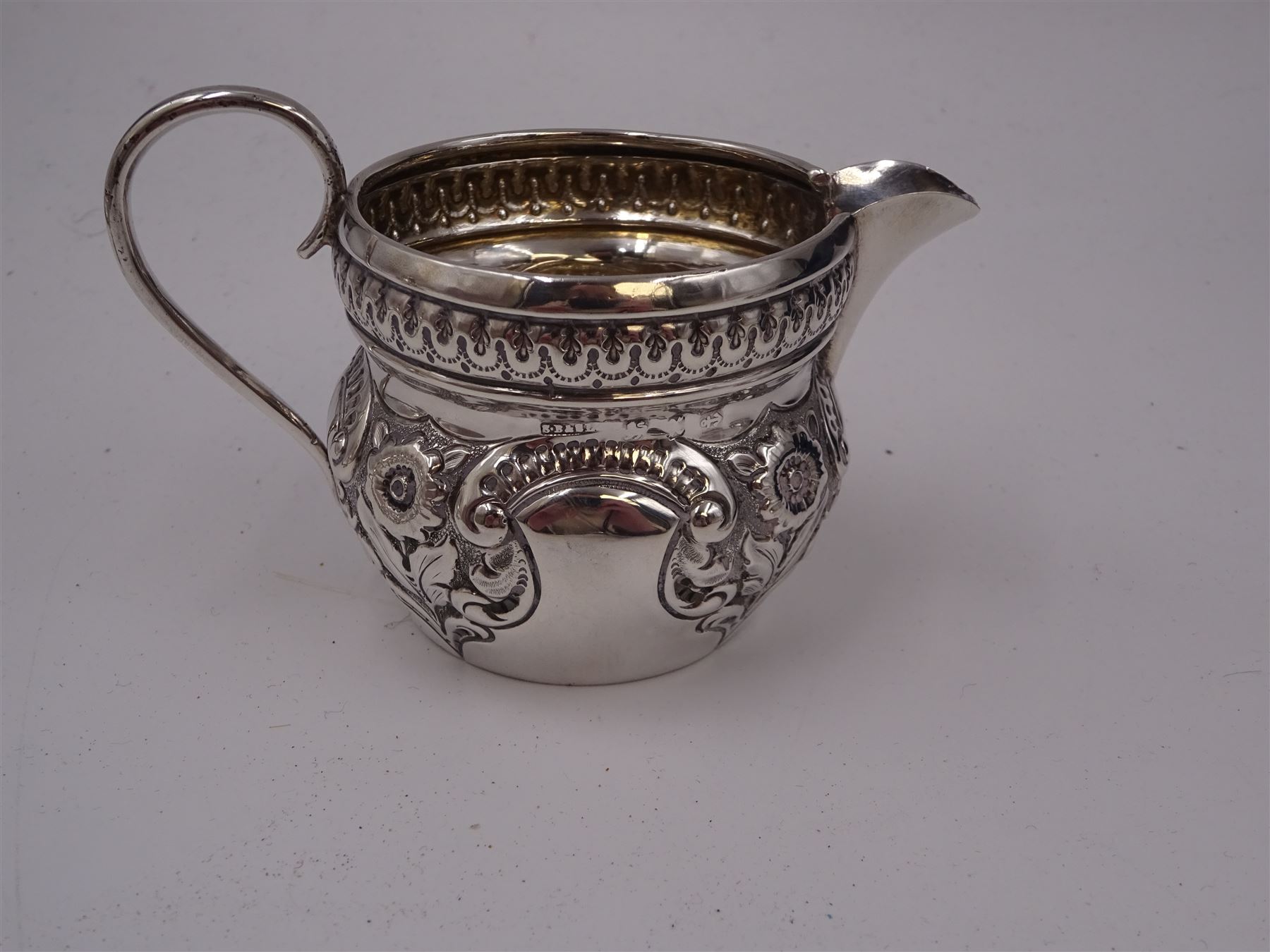 Group of silver, comprising pair of Edwardian silver open salts, of circular form, with repousse floral and C scroll decoration, and pair of matching salt spoons, hallmarked Joseph Gloster, Birmingham 1907, in tooled leather velvet and silk lined fitted case, together with a Victorian silver cream jug, of helmet form, with repousse floral decoration, hallmarked S Blanckensee & Son Ltd, Birmingham 1897, a mid 20th century silver bon bon dish, of circular form, with pierced sides, upon stepped foot, hallmarked Birmingham 1956, maker's mark worn and indistinct, a Victorian silver pepper, hallmarked Thomas Hayes, Birmingham 1895, and a silver thimble, stamped sterling