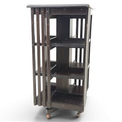 20th century ebonised revolving bookcase, square top with chamfered edges, over a three tier with four sections per tier,  revolving base on castors 