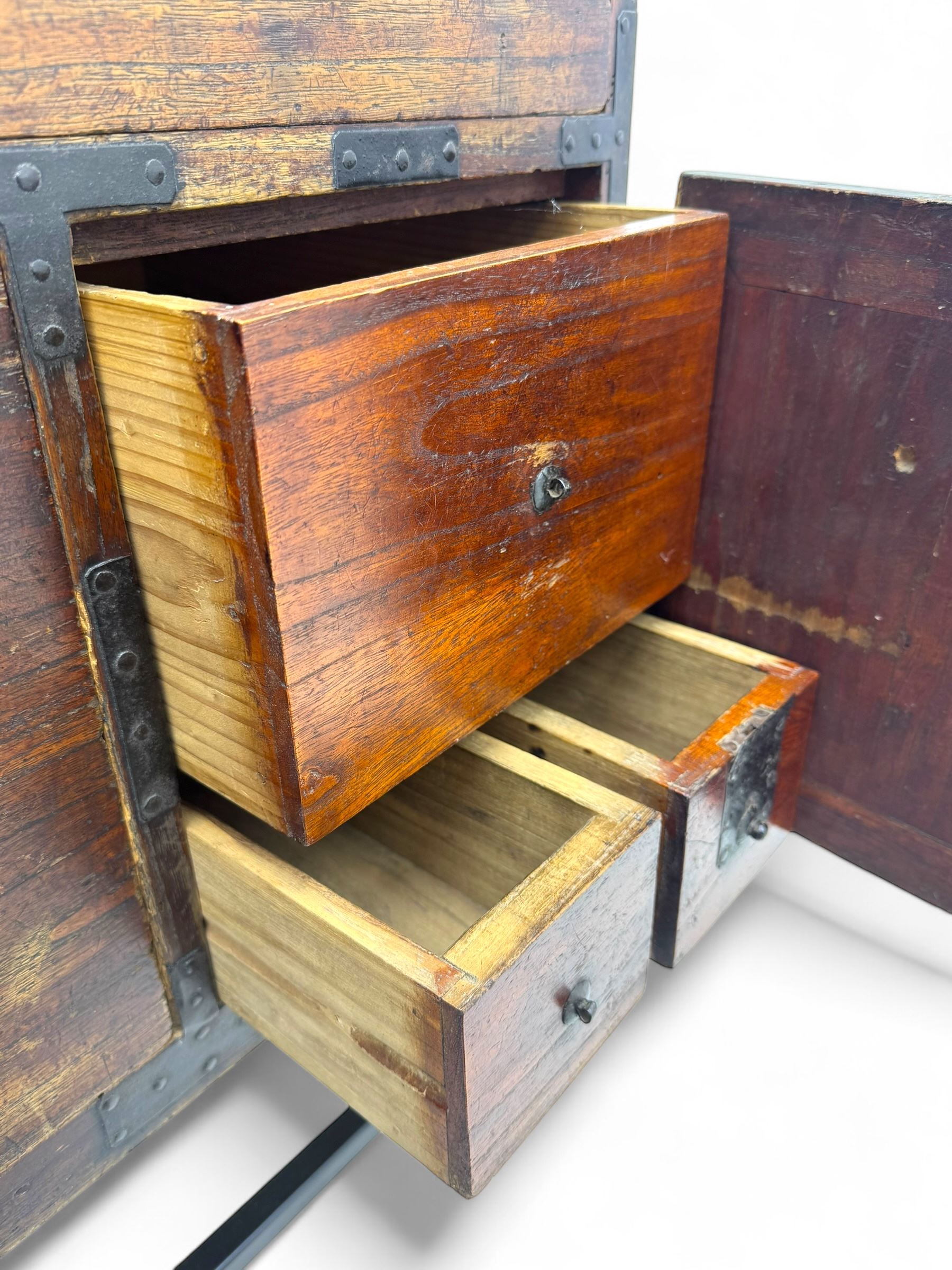 Late 19th century Japanese tansu chest, crafted with a cedar frame and cypress wood panels, original iron fittings throughout, comprising a single long drawer above smaller drawer and hinged cupboard door enclosing two smaller internal drawers and storage compartment, mounted on a bespoke black metal stand