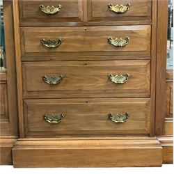 Edwardian walnut combination breakfront triple wardrobe, projecting cornice over cushioned and fluted frieze, central fielded panelled cupboard carved with foliate decoration above two short and three long drawers, flanked by two bevelled mirror doors enclosing hanging hooks with single drawers to base, retailed by J Tonks & Sons, Scarborough