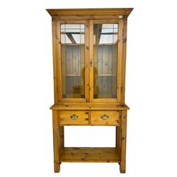 Traditional pine cabinet or bookcase on stand, fitted with two leaded stained glass doors enclosing adjustable shelves, base fitted with two drawers, raised on square chamfered supports united by undertier 