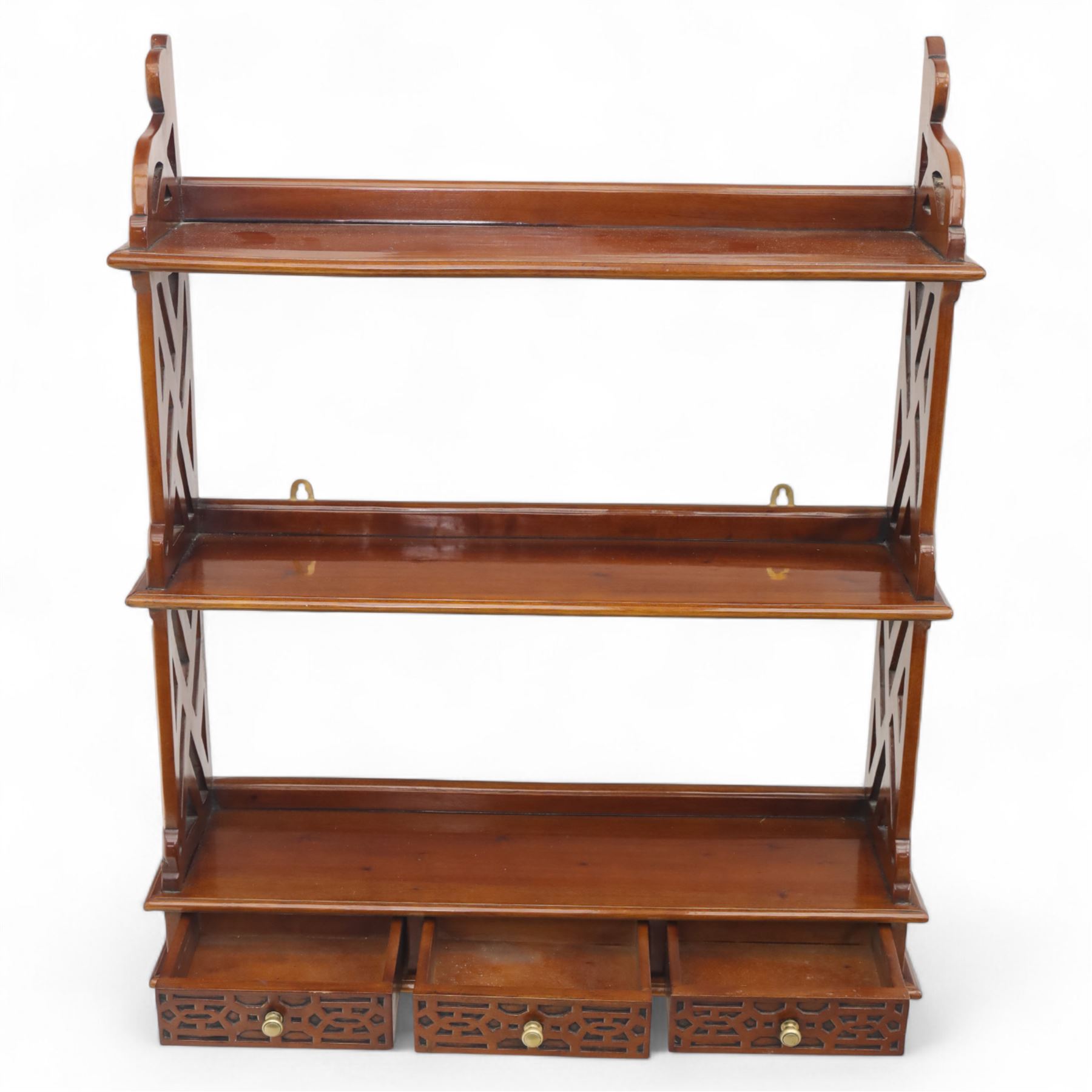 Two mahogany wall hanging items, comprising a French mahogany overmantel mirror with reeded uprights and moulded cornice (H 68cm, W 97cm, D 10cm), together with a mahogany wall shelf unit with three tiers and fretwork sides, the lower section fitted with three small drawers (H 95cm, W 63cm, D 18cm) (2)