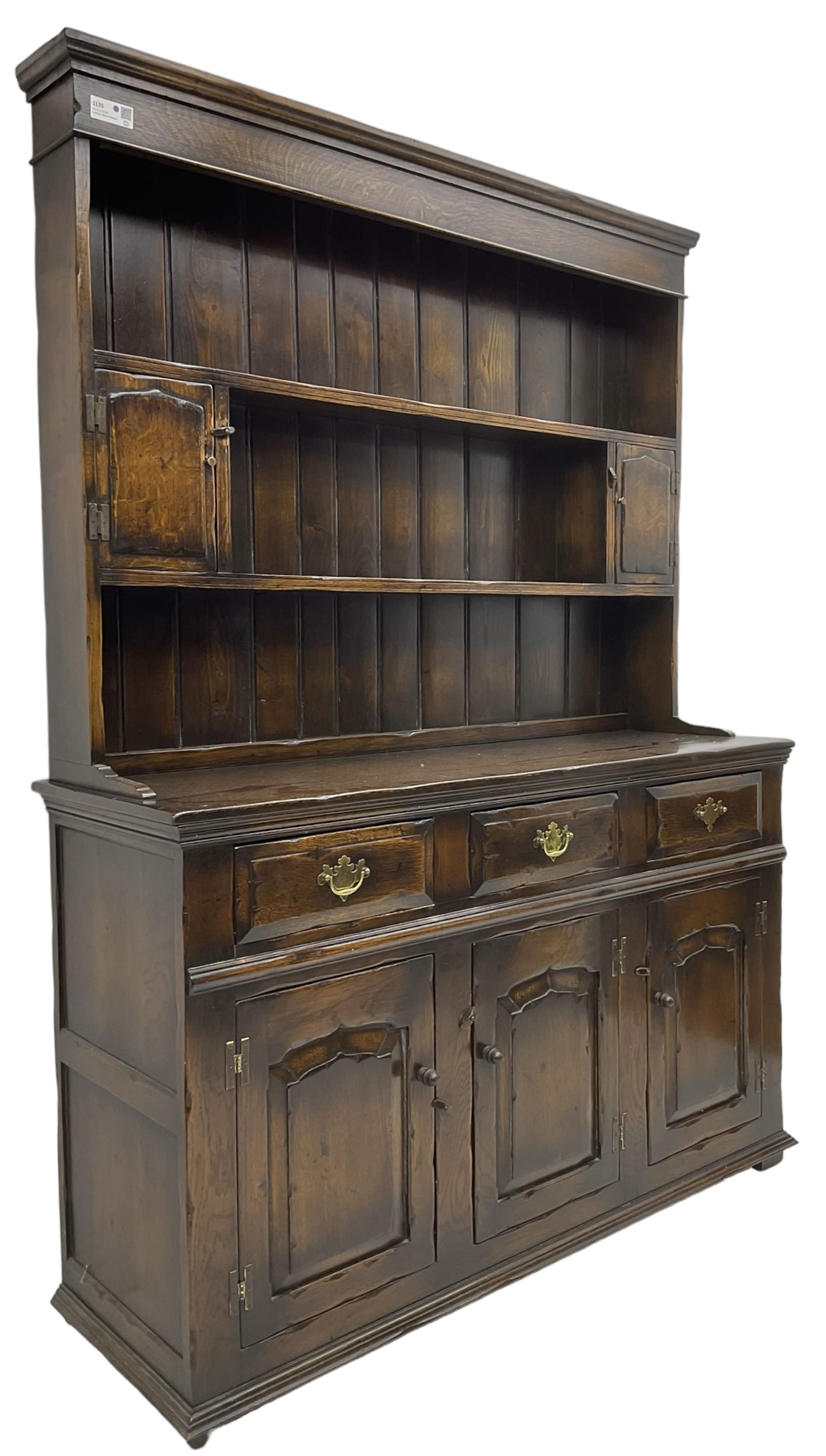 Georgian design oak dresser, the two-tier plate rack with two flanking spice cupboards, the base fitted with three drawers over three arched fielded panelled cupboards, lower moulded edge on block feet