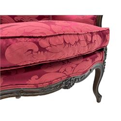 French style beech armchair, the moulded frame carved with flower heads and foliage, upholstered in red Damask fabric with floral pattern, shaped apron on scroll carved cabriole supports