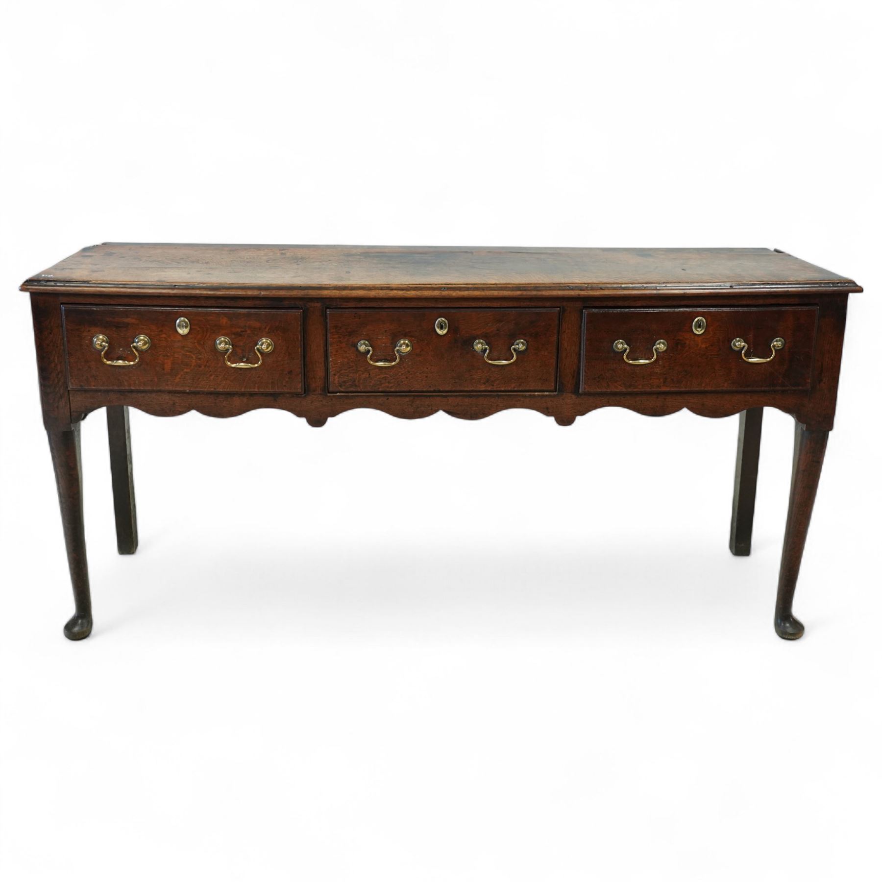 George III oak dresser base, fitted with three drawers with brass swan-neck handles, shaped apron and cabriole legs on pad feet 