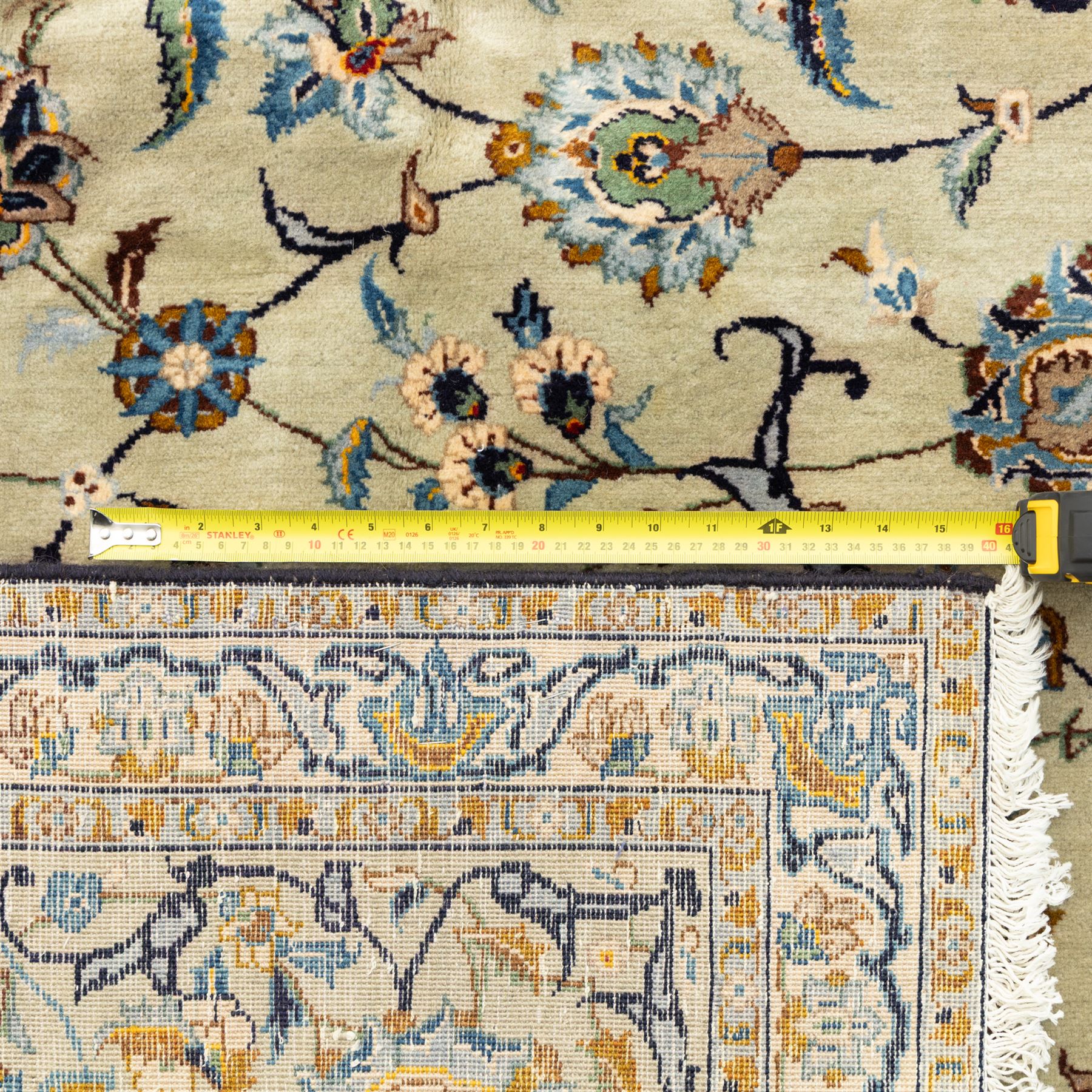 Persian Kashan rug, cream ground decorated with an all-over pattern of interlaced floral stems, rosettes and palmettes in blue, gold and rust tones, framed by layered floral borders, woven in the Kashan region of Iran