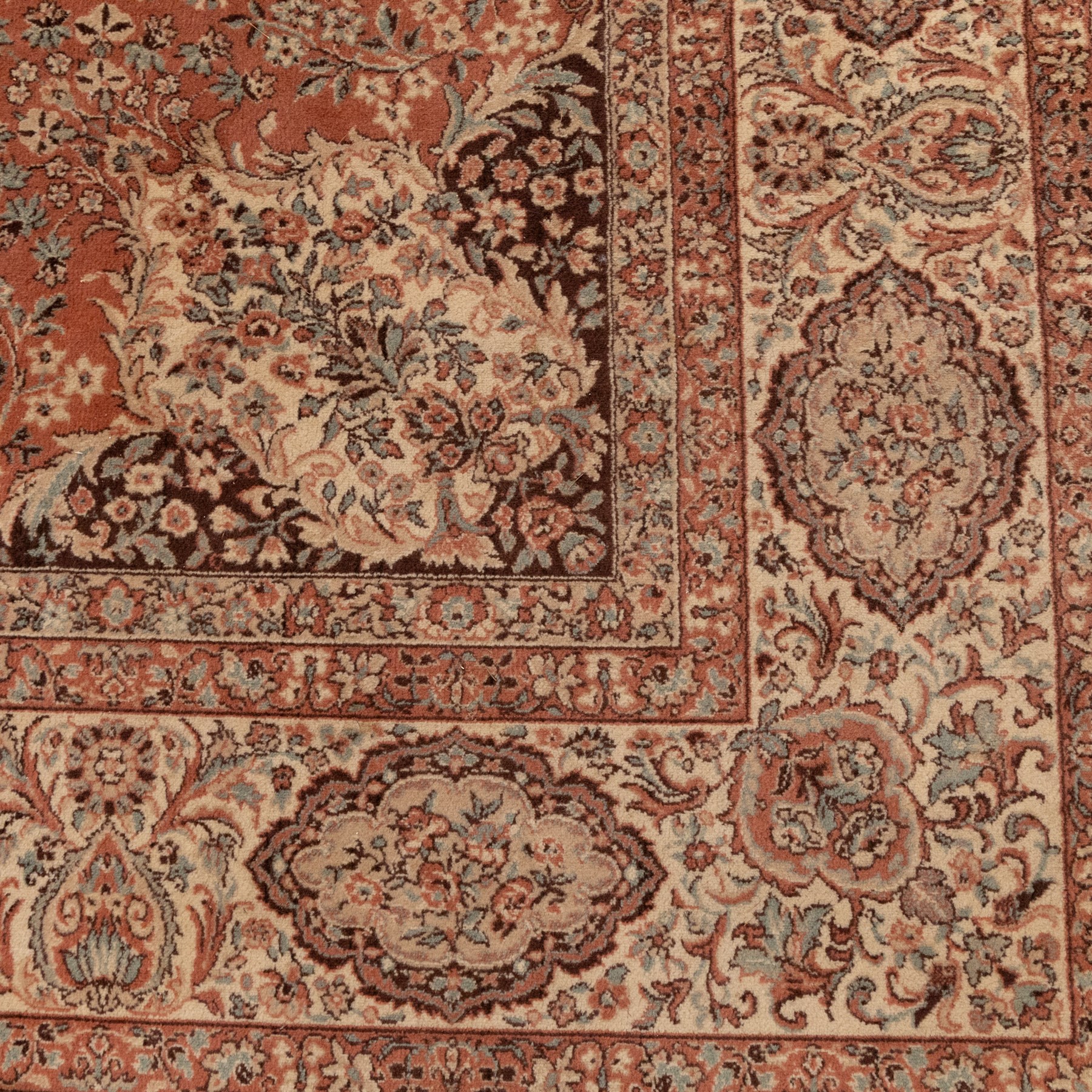 Persian vermillion ground Kashan rug, the busy field decorated with a central floral pole medallion, surrounded by trailing foliage and profusely woven floral patterns and bouquets, the dark indigo spandrels and multiple guard bands with similar floral decoration and stylised spandrels