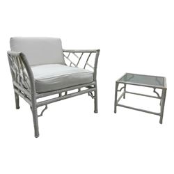 Late 20th century faux bamboo conservatory sofa, white painted frame with geometric openwork back and sides, loose cream cushions, on cylindrical supports (W134cm, D76cm, H80cm); matching armchair (W75cm, D76cm, H80cm); matching coffee table with glass insert (W46cm, D45cm, H36cm)