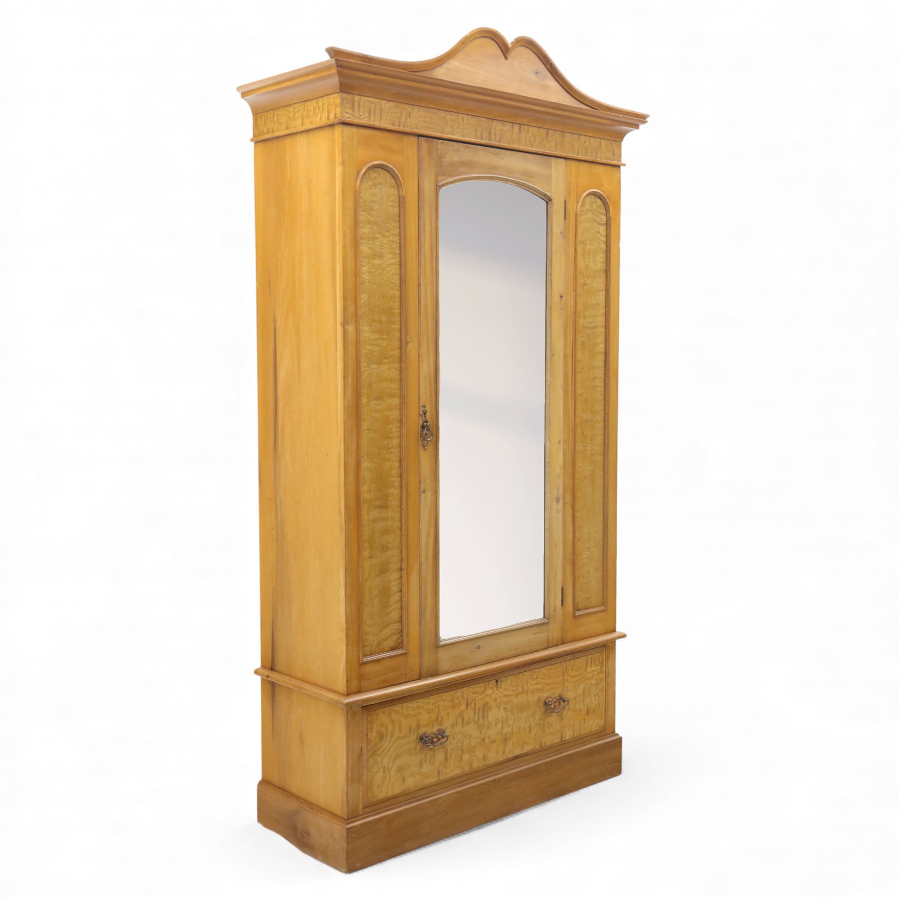 Victorian satin walnut single door wardrobe, shaped cavetto cornice above a central arched mirrored door flanked by recessed panelled sides, the interior fitted with hanging space and later added corner shelves, over a single long drawer with brass handles, on a plinth base