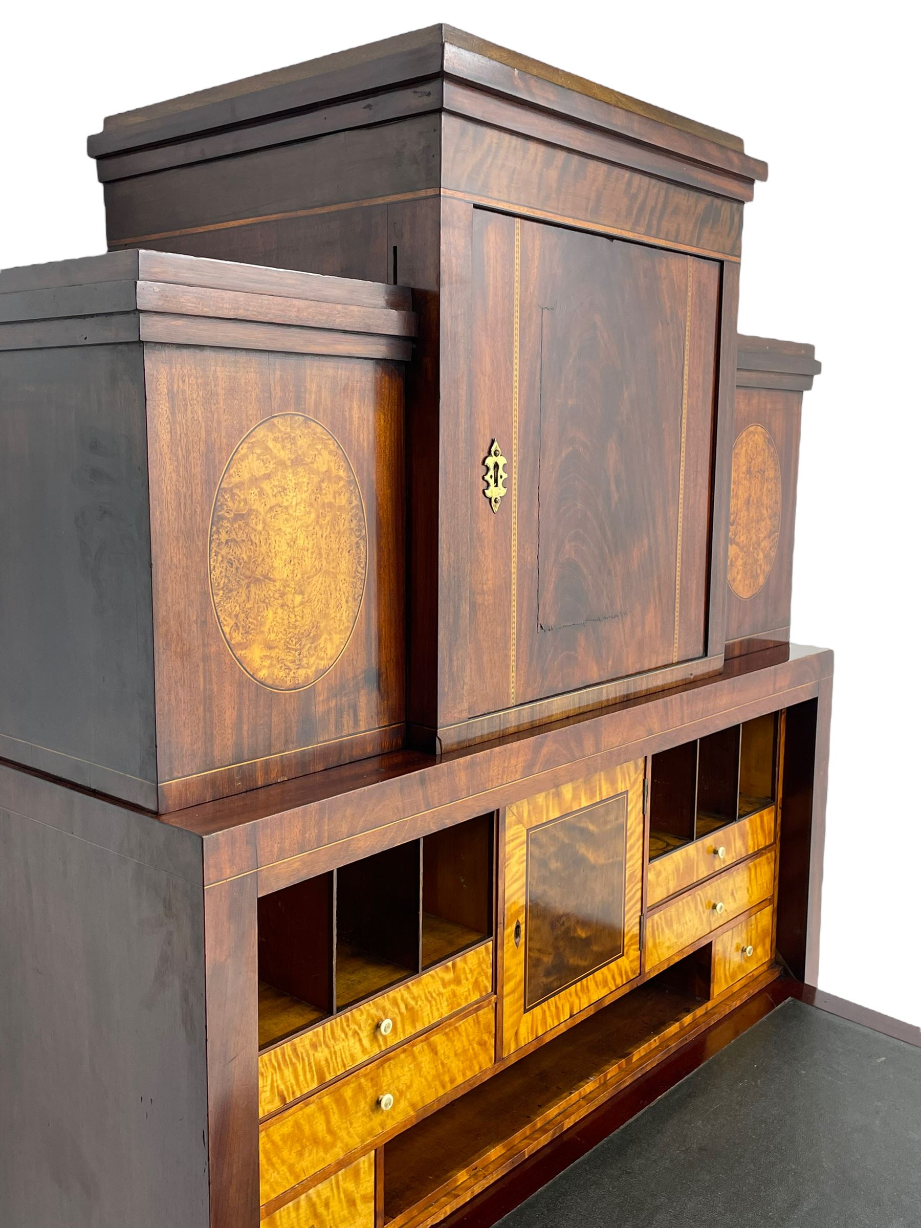 Early to mid-19th century figured mahogany Continental secrétaire à abattant, stepped top fitted with single cupboard, inlaid with oval figured amboyna panels, the fall front inlaid with shell motif enclosing a satinwood interior fitted with cupboard, drawers, and pigeon holes, three long drawers below, on square tapering feet
