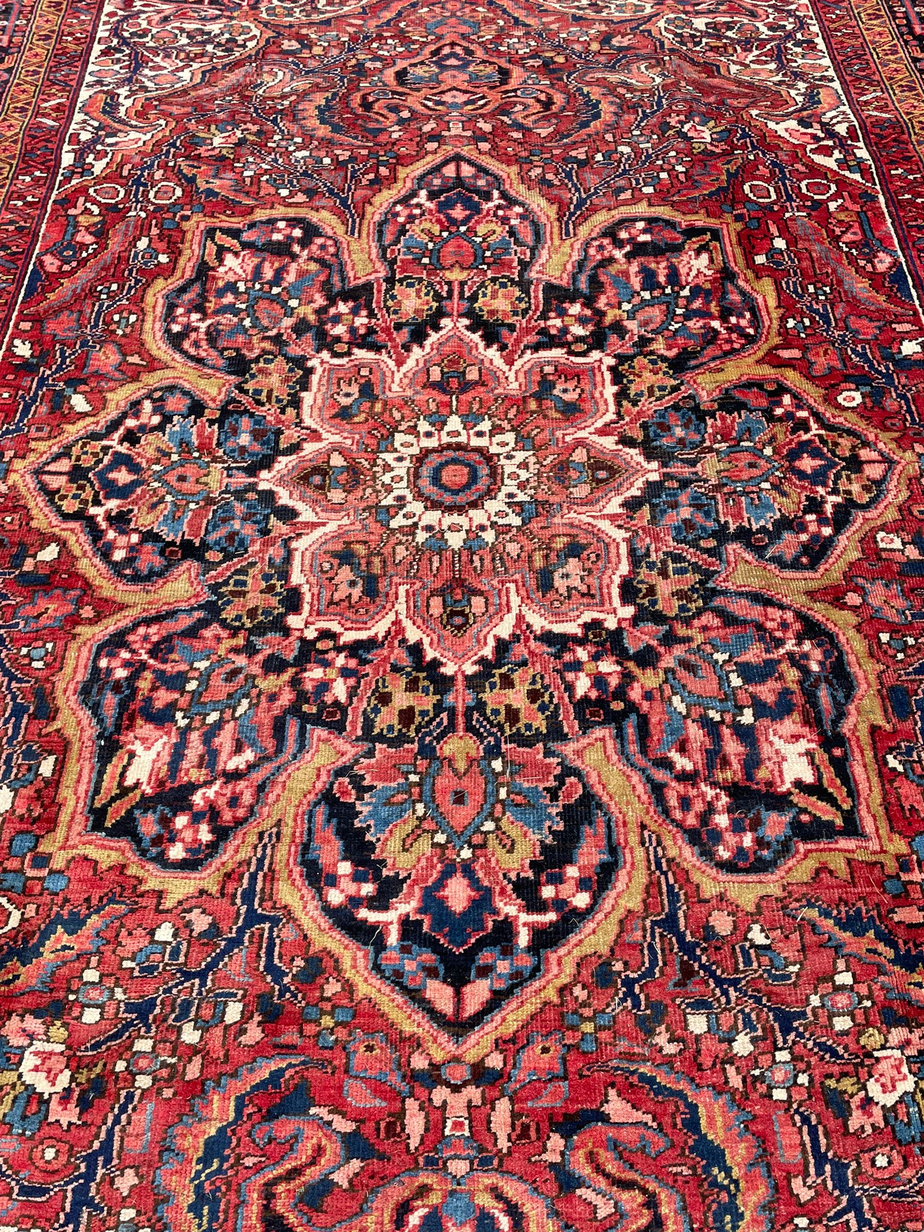 Antique Persian coral ground carpet, the large central floral pole medallion with extending foliate designs, the thick guarded indigo border with repeating flower heads and circles