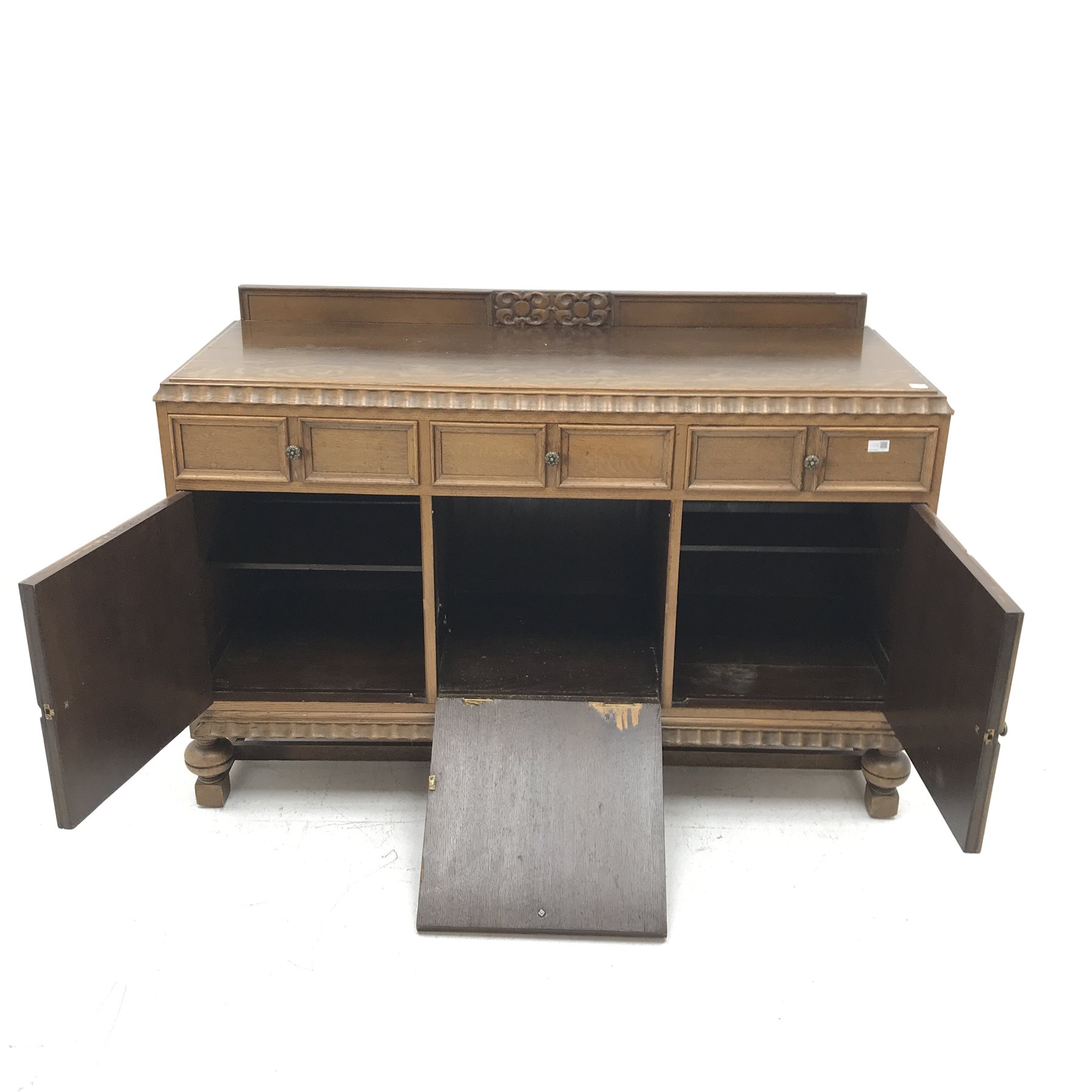 E. Gomme Ltd of High Wycombe oak sideboard, raised carved back, moulded top, three drawers above two cupboards flanking single fall front unit, turned supports joined by stretchers, W150cm, H101cm, D57cm