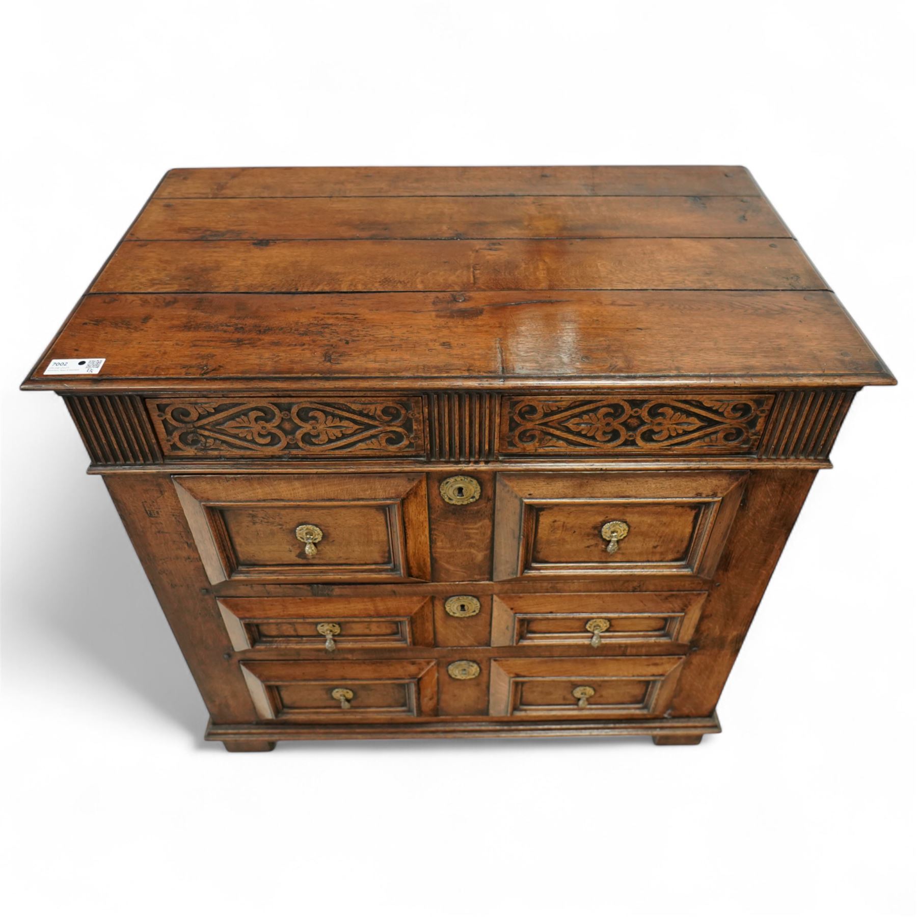 John Nethercott & Co - late 20th century hand-made oak 17th-century design chest of drawers, rectangular pegged and planked top above scrollwork carved frieze concealing two drawers, over three drawers, all with raised rectangular moulding and drop handles, raised on stile feet, the back with dated label for John Nethercott & Co