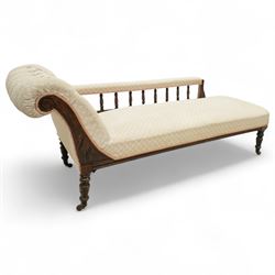Late 19th century cream upholstered chaise longue, patterned pale damask fabric, padded arm with spindle back gallery raised on turned legs upon castors