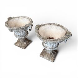 Pair of Neoclassical design cast stone garden urns, each of campana form with fluted body and gadrooned underbelly, decorated with faun/satyr opposing masks and ropetwist handles, with floral and mask design to the socles, raised on square bases, finished in weathered white patina