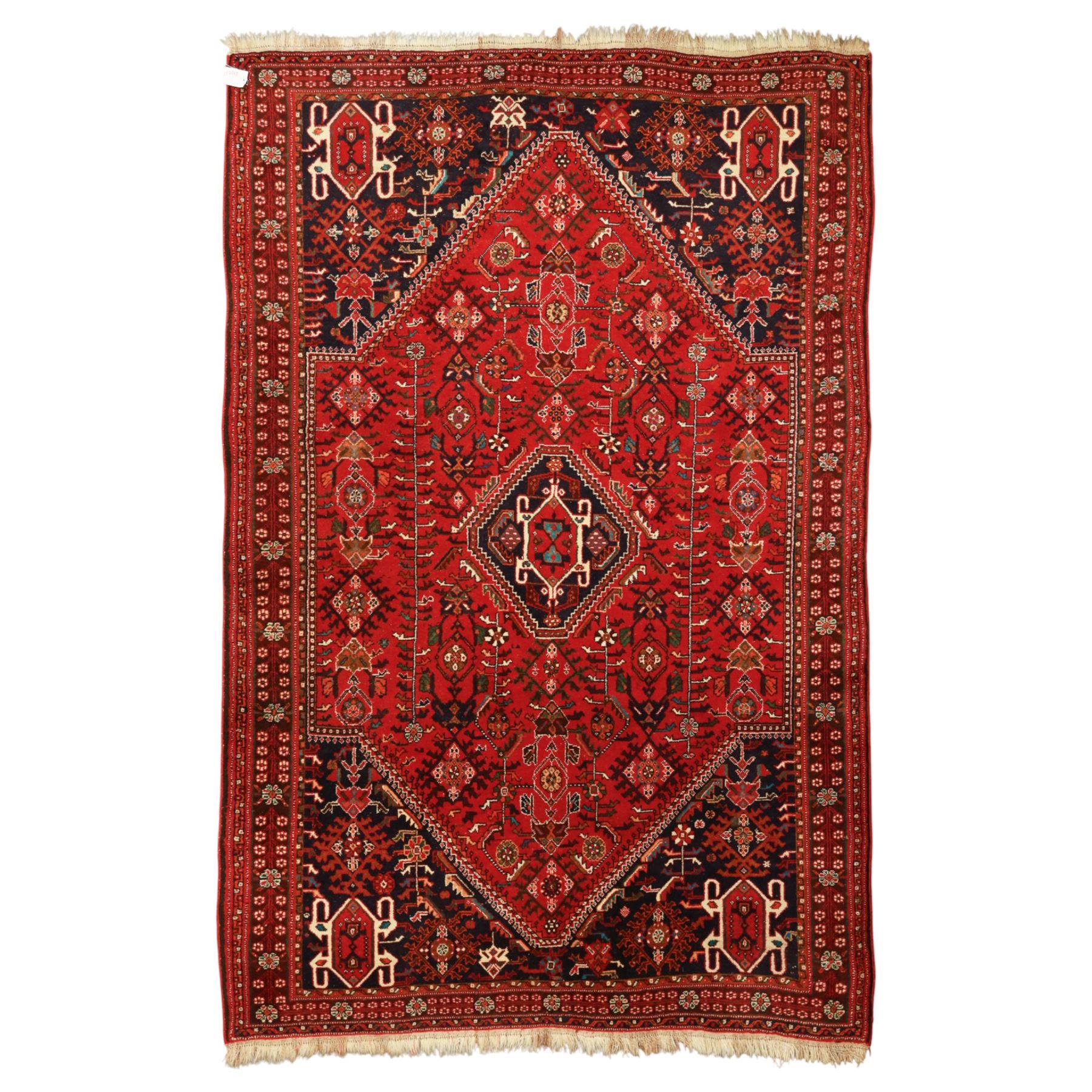 Persian tribal hand-knotted rug, crimson ground, madder field with central stepped lozenge medallion with scattered floral and geometric spandrels with rosette border 