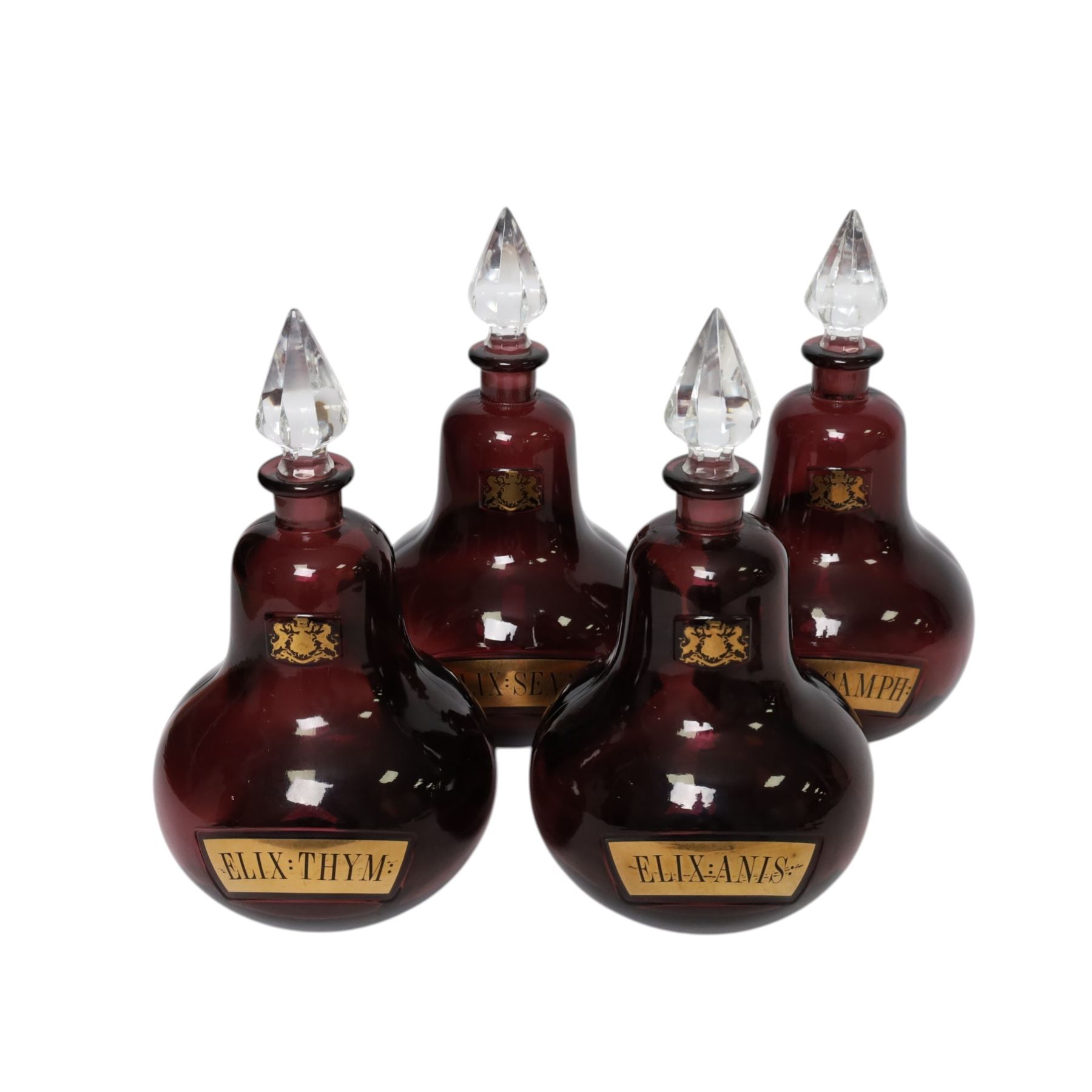 Set of four 20th century Royal Pharmaceutical Society amethyst glass bottles, of bellied form with clear cut glass spire stopper, each body bearing gilt label in Latin: ELIX:THYM:, ELIX:CAMPH:, ELIX:ANIS: and ELIX:SENN:, and gilt Royal Pharmaceutical Society crest to neck, H25cm

Provenance: From the collection of the family of Peter Green, a practising pharmacist whose career spanned the mid to late 20th century. During his professional life he managed pharmacies in Yeovil, Somerset, and later Selles Chemist in Filey, North Yorkshire, before purchasing and running his own business, Peter Green Pharmacy, located in the Market Place, Malton. The bottles were displayed as part of the traditional shop fittings in both the Filey and Malton pharmacies and were retained as part of his collection.