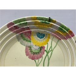 Clarice Cliff plate decorated in the Rhodanthe pattern in pink, yellow and green colourway on cream ground, together with a cylindrical preserve jar and cover decorated in the My Garden pattern with orange and yellow flowers on plain ground, both with factory stamps to reverse, jar H10cm, plate D28cnm