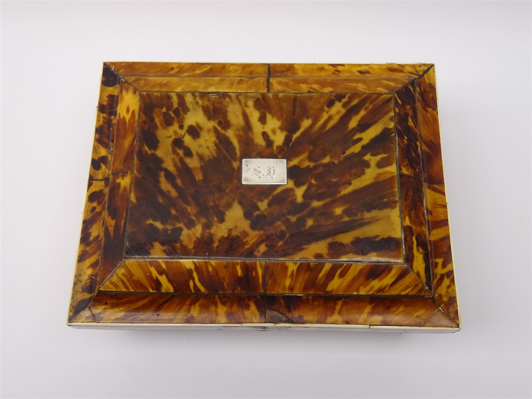 19th century tortoiseshell sewing box, of sarcophagal form upon four foliate detailed brass ball feet, the hinged cover edged in ivory with initialled silver plaque to centre, opening to reveal a silk lined interior, H9.5cm W22.5cm D18cm