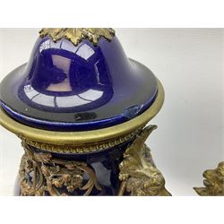 Pair of French large cobalt blue lidded urns, probably 19th century, the body decorated with ormolu ram's heads and ornate foliate design, the domed cover with brass berry finial, raised upon pedestal base with beaded decoration upon shaped plinth, H52cm