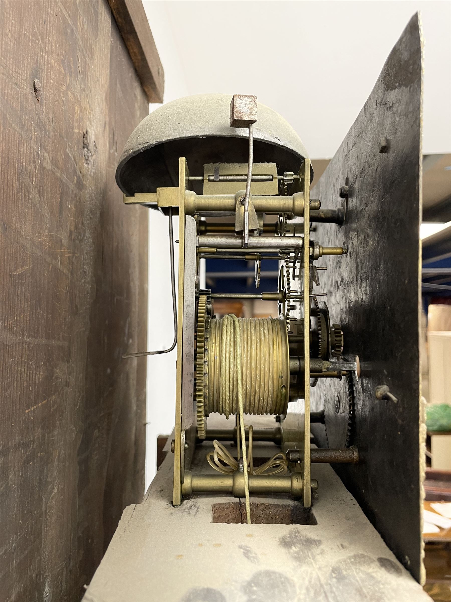 19th century carved oak longcase clock, projecting cornice over guilloche carved frieze, square brass dial with silvered Roman chapter ring and calendar aperture, decorated with ornate mask cast spandrels, the trunk door and base carved with potted plant, twin train driven eight day movement striking on bell