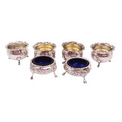 Pair of Victorian silver open salts, of cauldron form, with repousse and chased floral decoration, upon three trefid feet, hallmarked William Hutton & Sons, Sheffield 1883, with blue glass liners, together with a set of four Victorian silver open salts, of circular form, with C scroll rim and upon three pad feet, two with gilded interiors, hallmarked Edward Barnard & Sons Ltd, London 1900, tallest H3.5cm