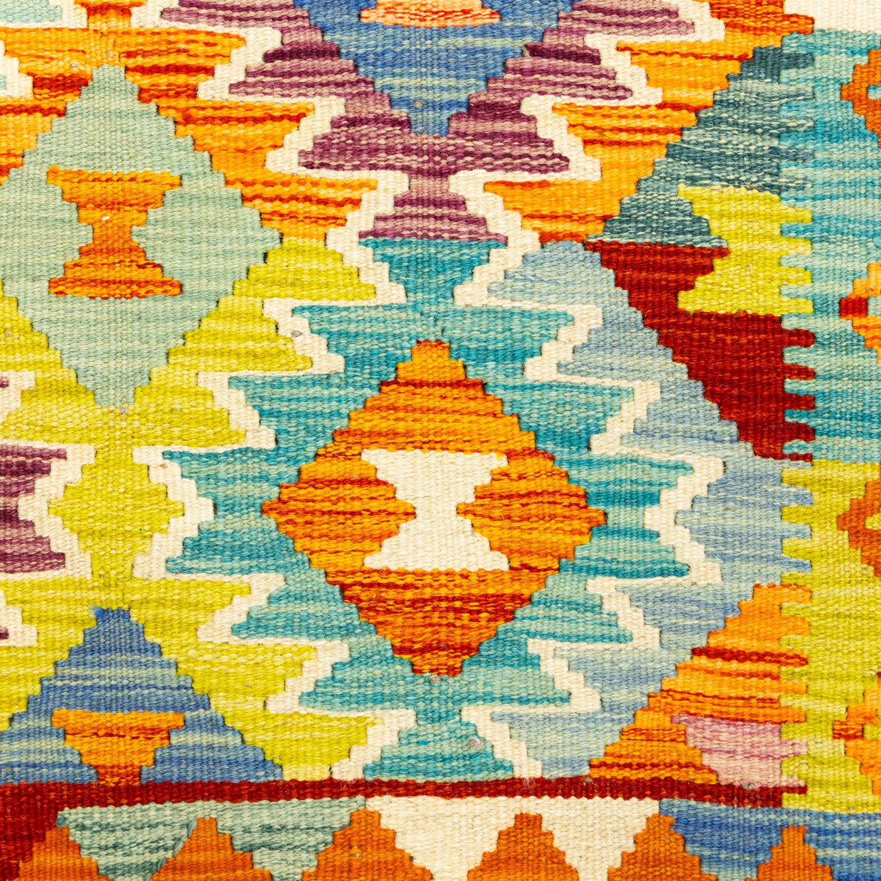 Afghan Chobi kilim flatweave runner with a repeating stepped diamond medallion design in live green, rust, teal, purple, and ivory, framed by chevron and geometric borders
