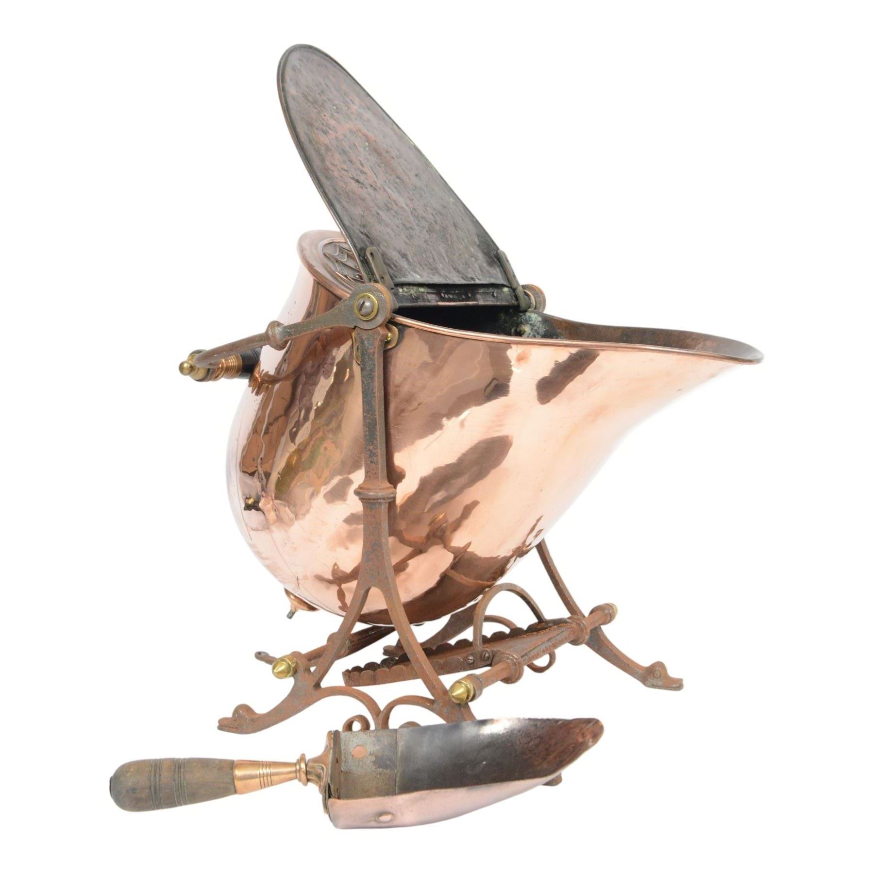 Victorian copper coal scuttle, the helmet shaped body tilting upon stand, with embossed hinged cover, turned wood handle and scoop H53cm
